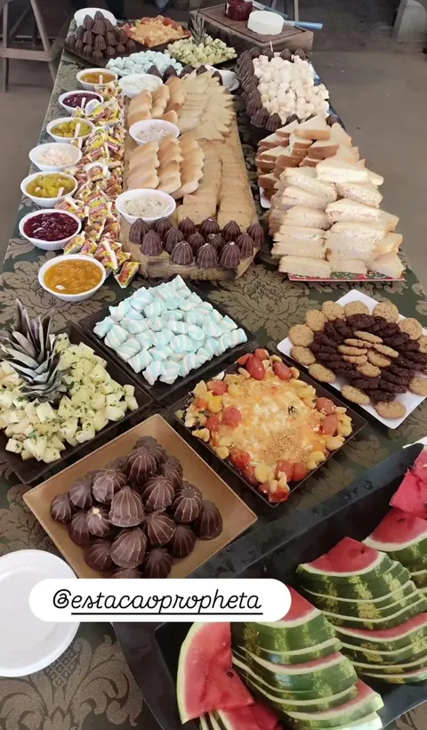 Mesa longa com salgados, doces e frutas